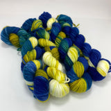 Four skeins of variegated yarn in blue, teal, acid green and white.