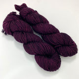 Two mini skeins of deep purple tonal worsted weight yarn. 