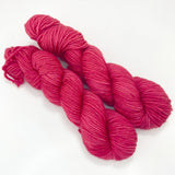 Two mini skeins of deep bright pink 
tonal worsted weight yarn. 