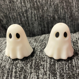 Two silicone stitch stoppers in the form of 3d white ghosts with large black eyes.  