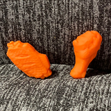 Two silicone stitch stoppers in the form of chicken wings, orange like buffalo sauce.  