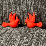 Two silicone stitch stoppers in the form of red cardinals in flight.  