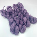 Four mini skeins of medium dusty purple yarn.