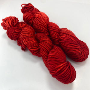 Two mini skeins of deep red tonal worsted weight yarn. 