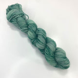 A mini skein of variegated and speckly green yarn.