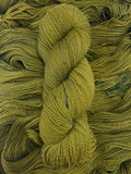 A skein of yarn sits vertically atop a bed of the same yarn laid out with the strands running horizontally.  The yarn is all a tonal acid green colour shot through with splashes of deeper green.  