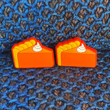 Two silicone stitch stoppers in the two-dimensional shape of slices of pumpkin pie.